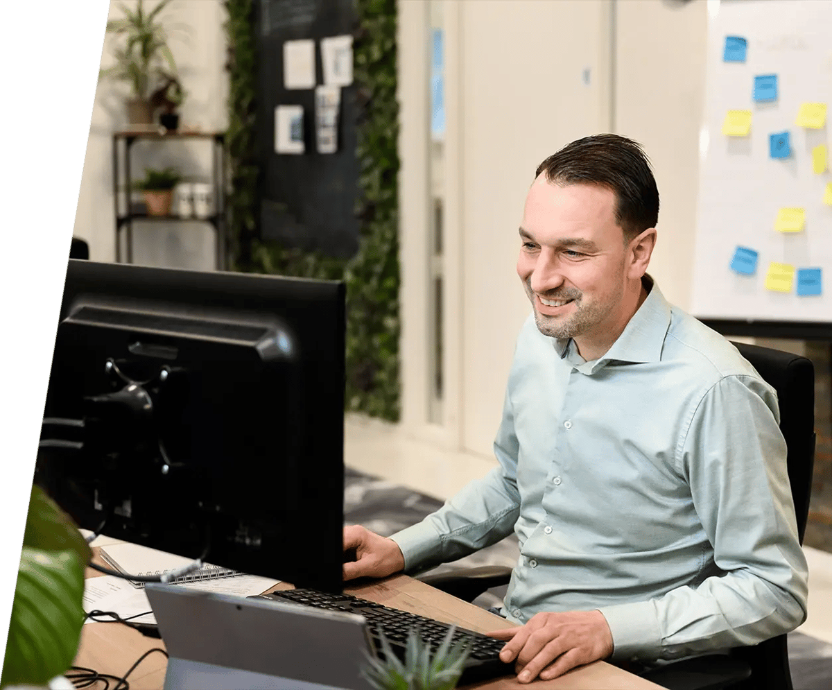 Een vrolijke man die met plezier achter zijn laptop werkt