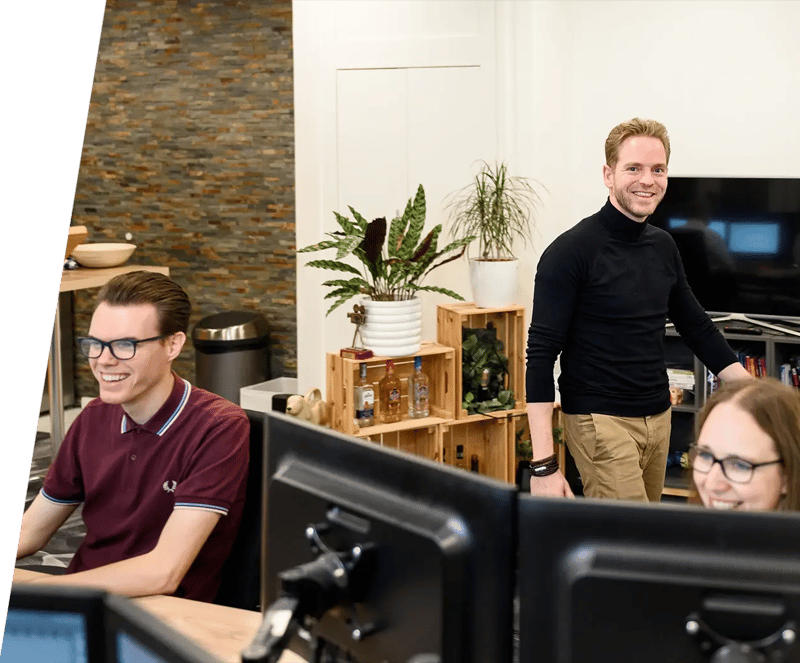 Een Ha marketeer loopt achter een collega langs die werkt aan het SEO vriendelijk maken van een mobiele website