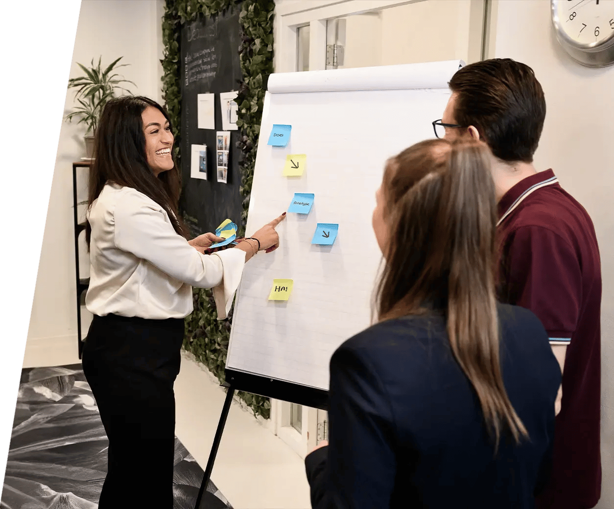 Een lachende vrouw leidt een interactieve brainstormsessie met twee collega's